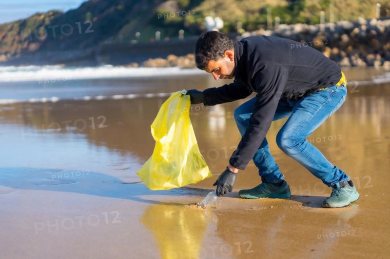 Volunteer man collecting garbage or plastic on the beach. ecology concept