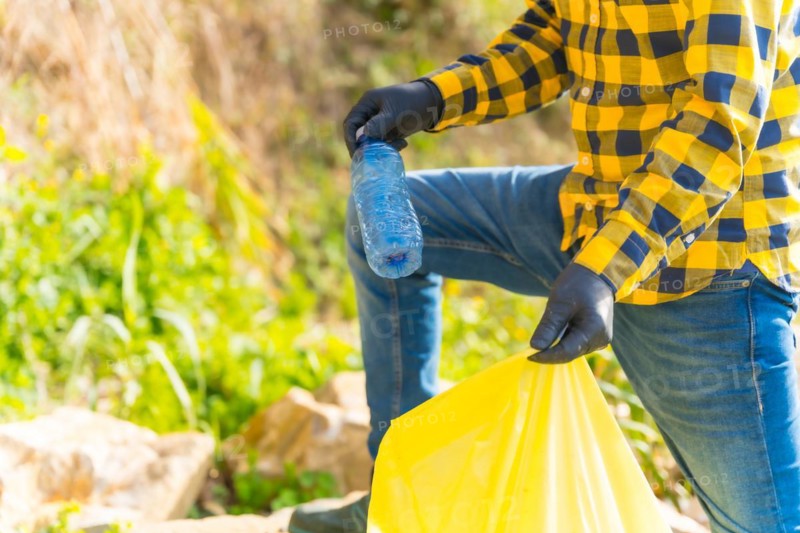 Unrecognizable man collecting plastics in a forest. Ecology concept