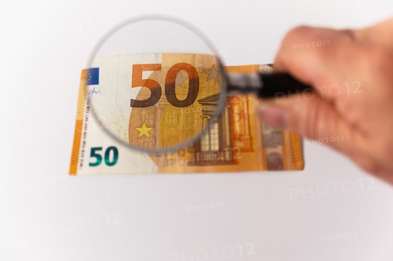 Fifty euro banknote seen with a magnifying glass on a white background and copy space