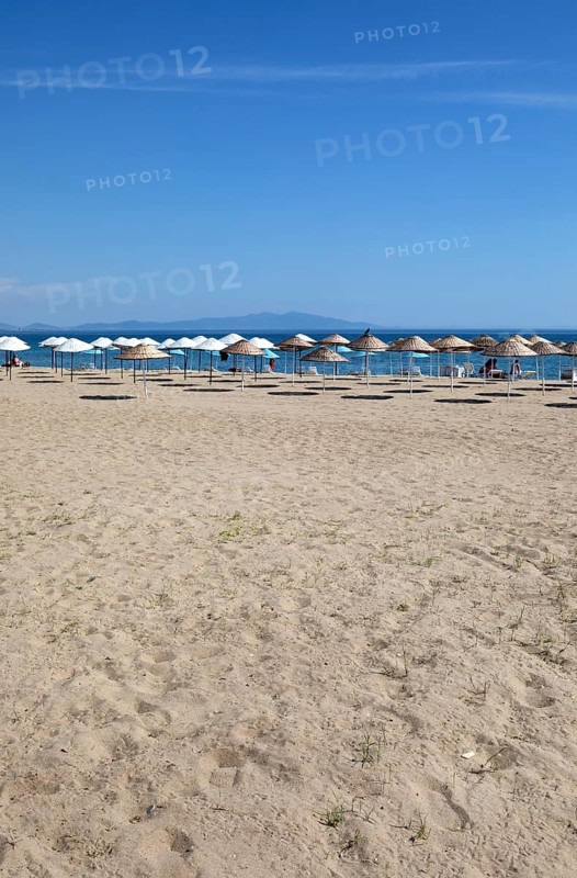 Straw parasols on the sandy beach on the Aegean Sea