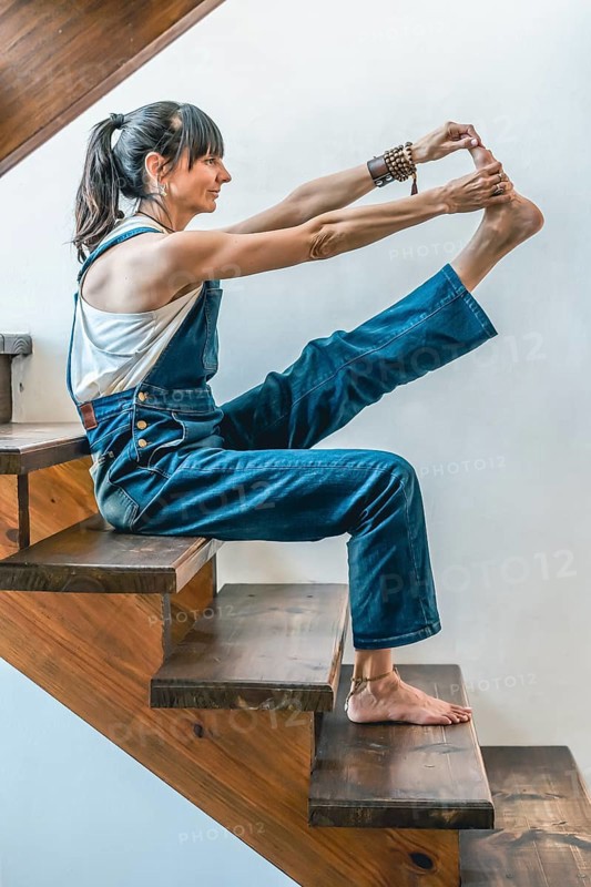 A woman doing stretching exercises on the stairs of her home. Wellbeing concept