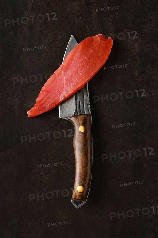 Slice of air dried turkey meat on the blade of knife