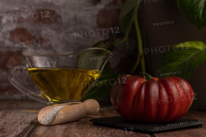 Chopped Moorish tomatoes with jar of olive oil and wooden spoon with salt