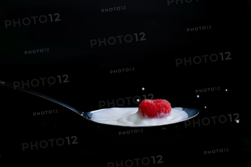 Raspberry splashing milk on a metal spoon splash effect with black background
