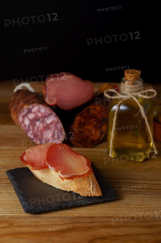 Tapa of iberian loin on rustic bread with olive oil on a black slate with black background
