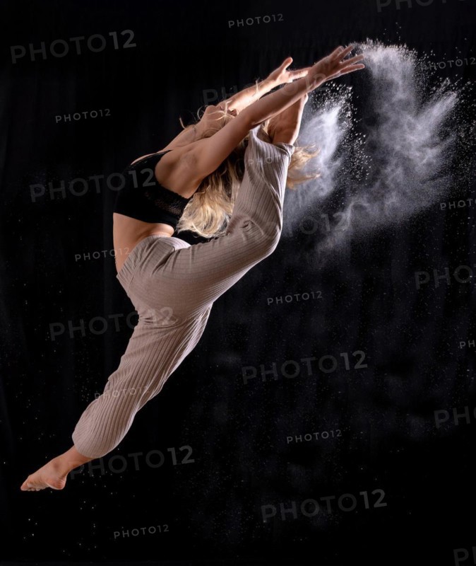 Young dancer performing a jump on a black background