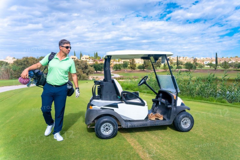 Man in the Buggy with the bag of clubs looking at the course