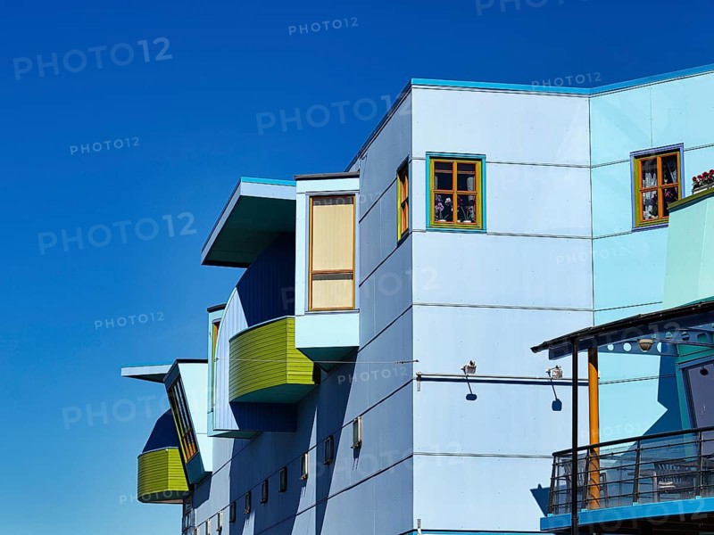 Light blue facade with colourful windows and balconies