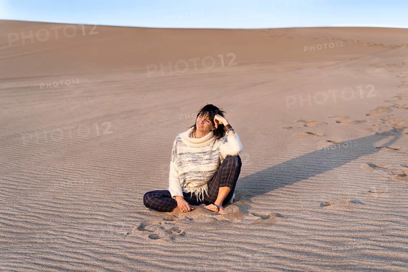 A woman is watching the sunset on a dune. Copy space