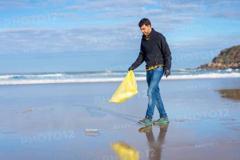 Man collecting garbage or plastic on the beach. Ecology concept