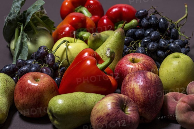 A collection of different colourful vegetables and fruits on a dark background