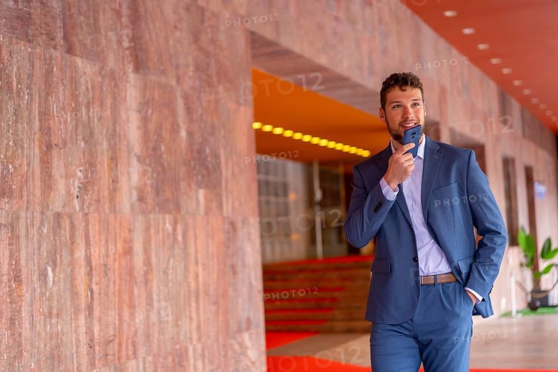 Business or finance corporate man at the entrance of an event in a hotel with the phone