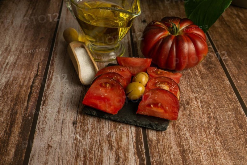 Chopped Moorish tomatoes with jar of olive oil and wooden spoon with salt