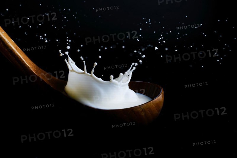 Milk splashing on a wooden ladle