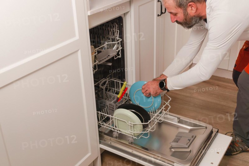 Man in white t-shirt putting the dishes in the dishwasher
