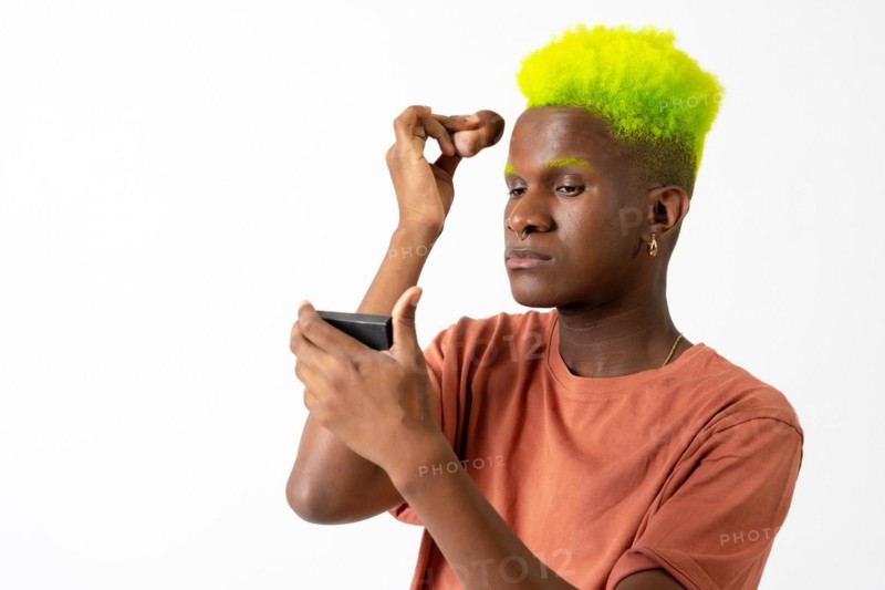 An androgynous black man posing putting on makeup