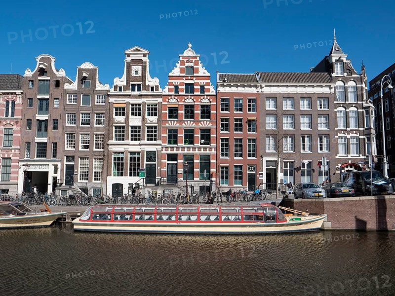 Historic merchant houses on the Herengracht in the old town and tourist boat