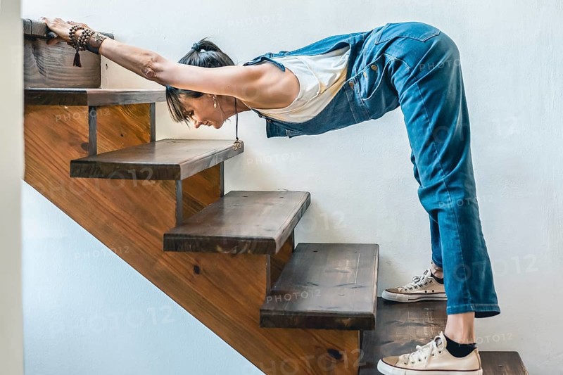 A woman doing stretching exercises on the stairs of her home. Wellbeing concept