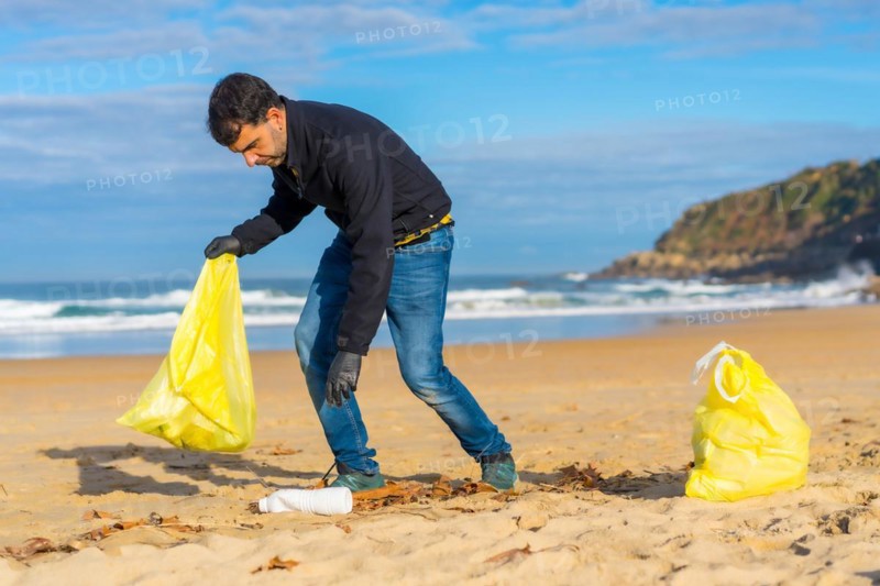 Volunteer person collecting plastic from the sand on the beach. Ecology concept