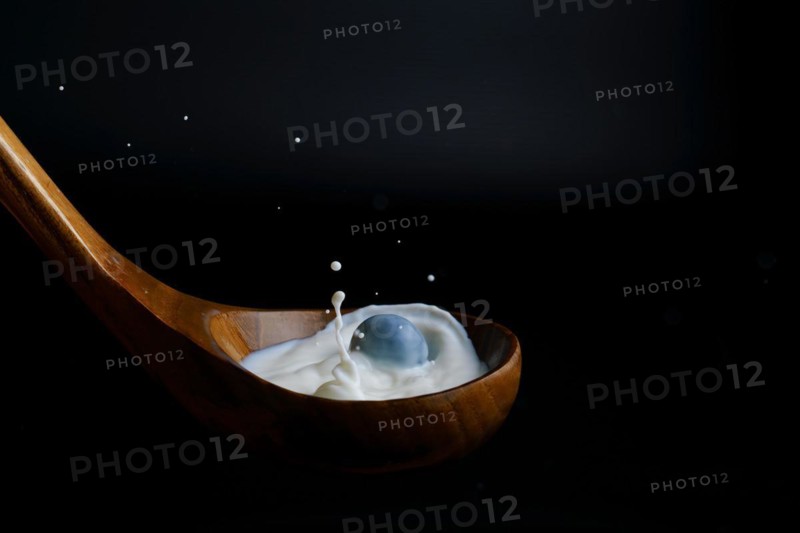 Blueberry splashing milk on a wooden dipper