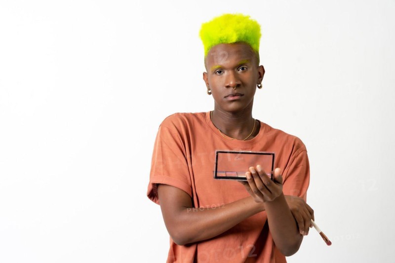 A gay black man putting on makeup