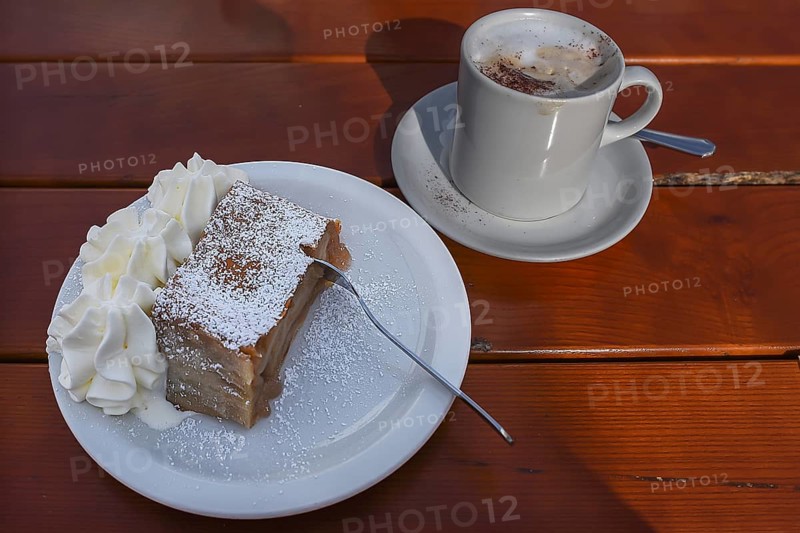 Apple strudel with cream and a cup of cappuccino served in a cafe