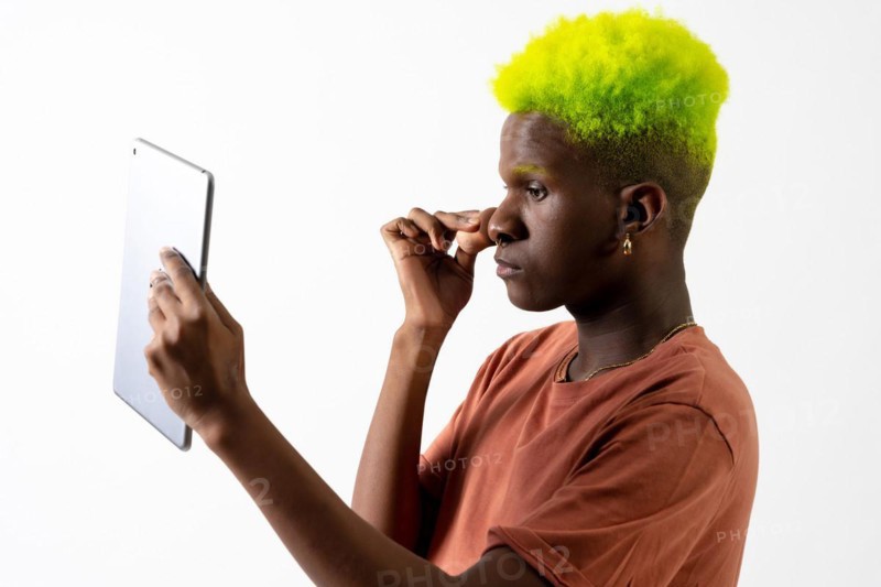 A gay black ethnic man putting on makeup