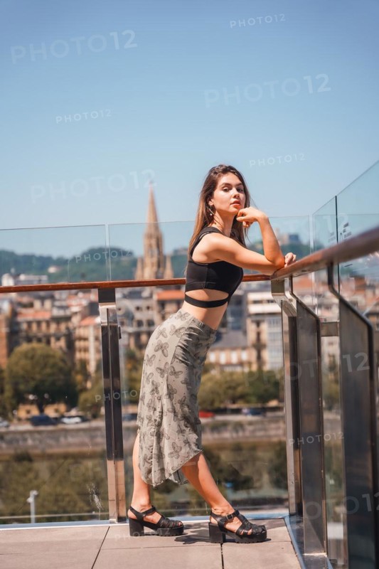 Posing of a young woman on the terrace of a hotel looking at the city from above