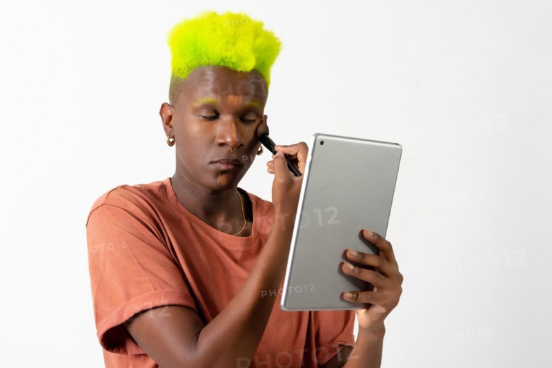 A gay black man putting on makeup