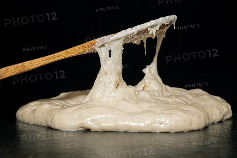 Bamboo spoon and baking dough with yeast