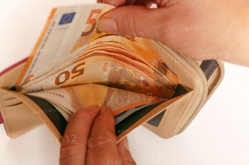Woman's hands taking euro banknotes out of her wallet with white background and copy space