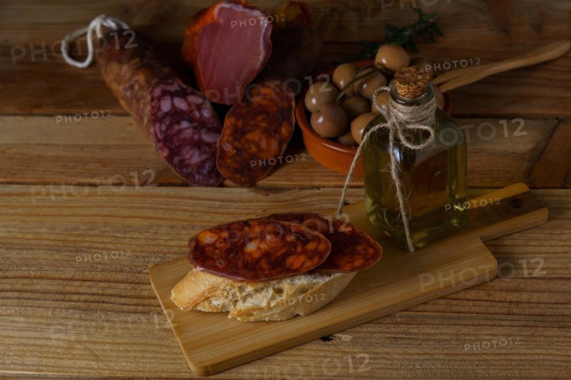 Tapa of iberian chorizo on rustic bread with olive oil on a wooden board with black background