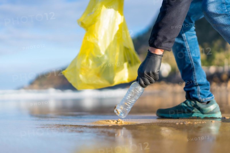 Unrecognizable person collecting garbage or plastic on the beach. ecology concept