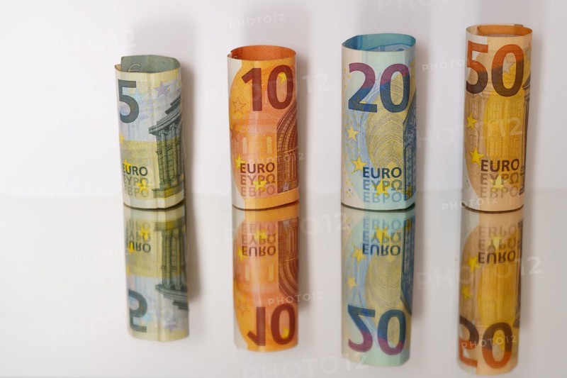Rolled euro banknotes reflected in a mirror with copy space