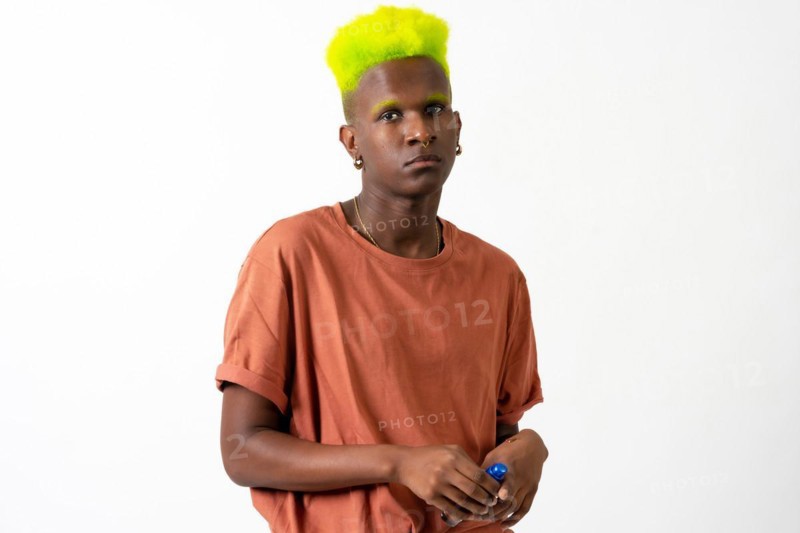 An androgynous black man posing in a studio on a white background