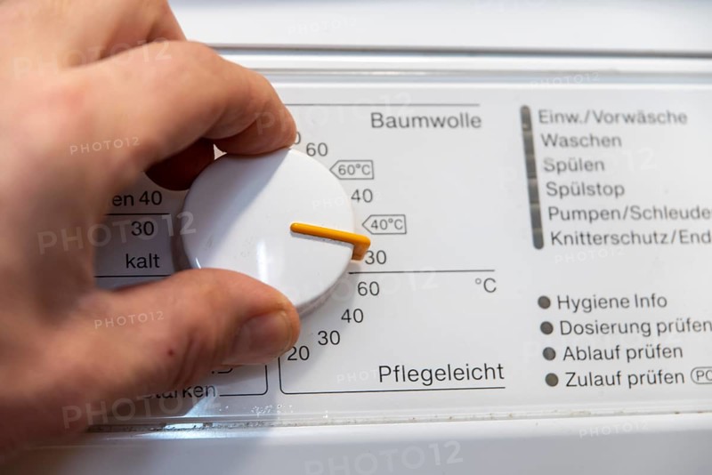 Hand on the temperature control of a washing machine