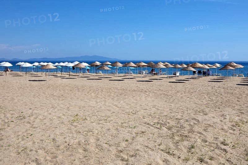 Straw parasols on the sandy beach on the Aegean Sea