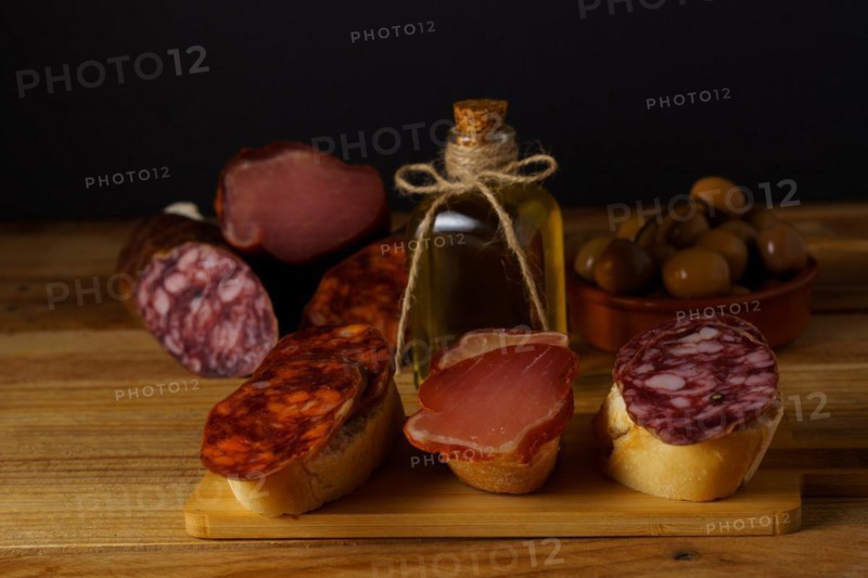 Assorted iberian sausage tapas on a wooden board with a black background