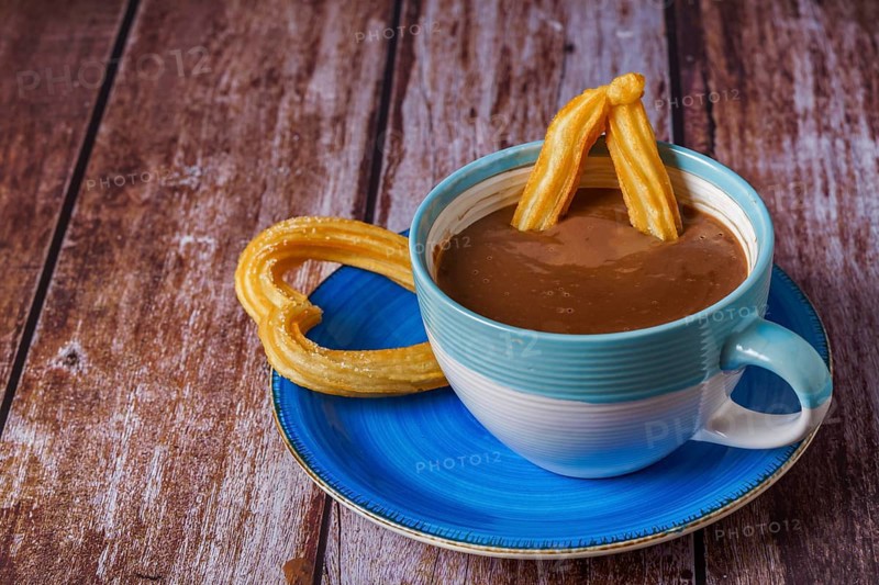 Hot chocolate with a churro in the form of a heart on a wooden table