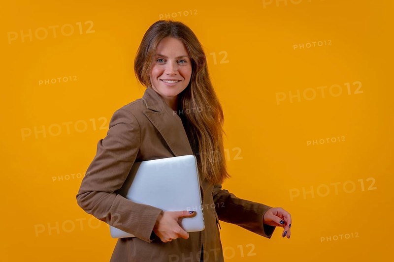 Portrait of a businesswoman with a computer or laptop on a yellow background