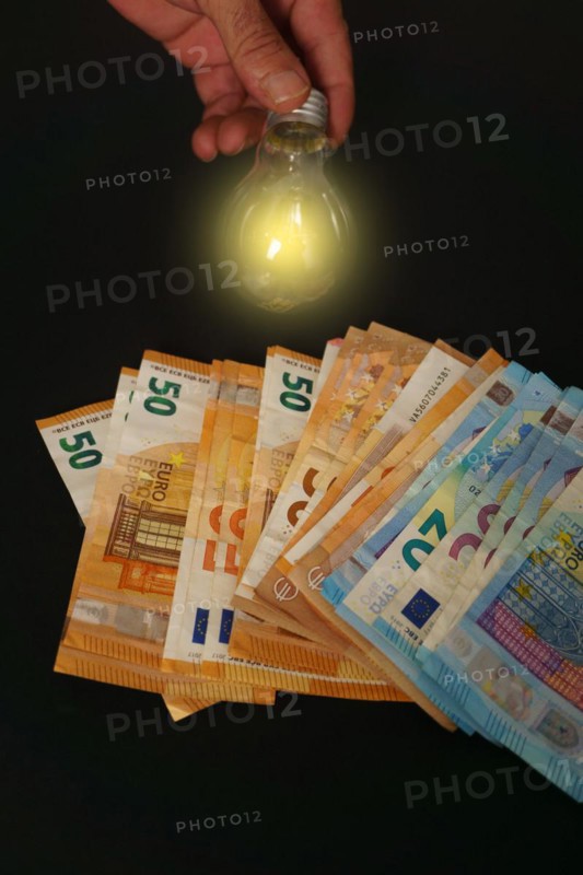 Lighted light bulb with euro banknotes in the background on a black background