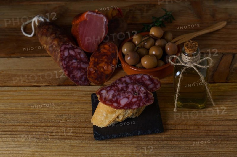 Tapa of iberian sausage on rustic bread with olive oil on a wooden board with black background