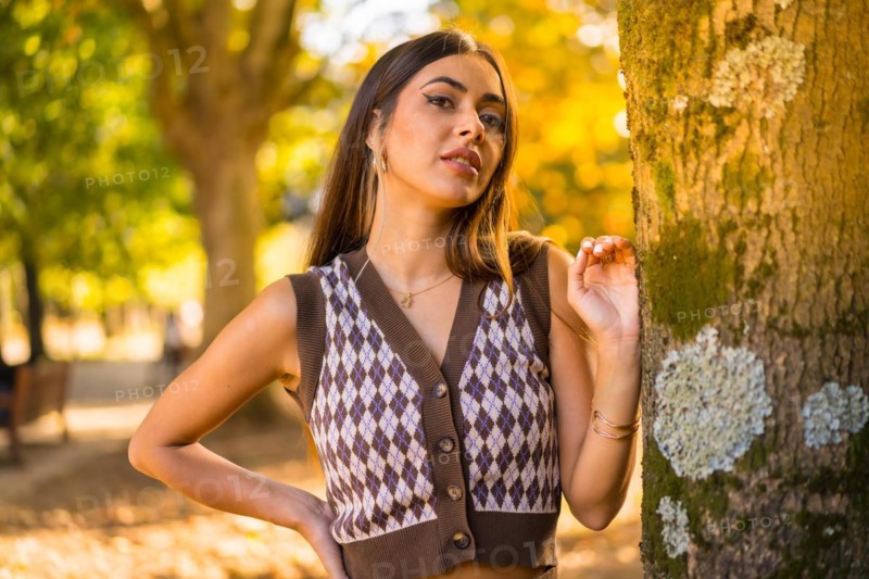 Brunette model in autumn at sunset in a natural city park