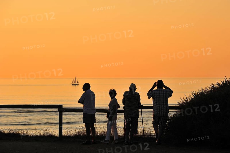 Tourists looking at sailing ship at sunset at Saint-Denis-d'Oleron on the island Ile d'Oleron