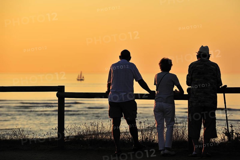 Tourists looking at sailing ship at sunset at Saint-Denis-d'Oleron on the island Ile d'Oleron