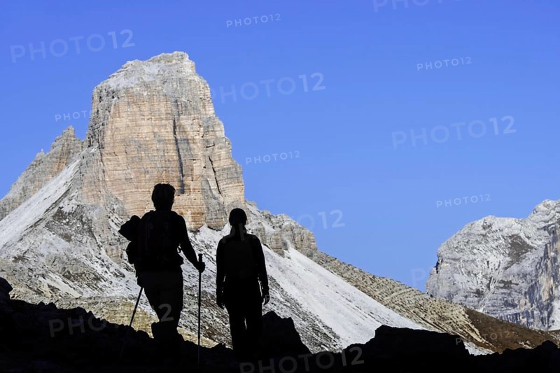 Two mountain walkers silhouetted against Torre dei Scarperi