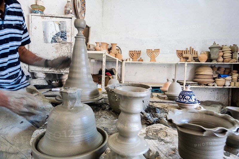 Skillful potter forming a vessel out of gray clay in a pottery factory