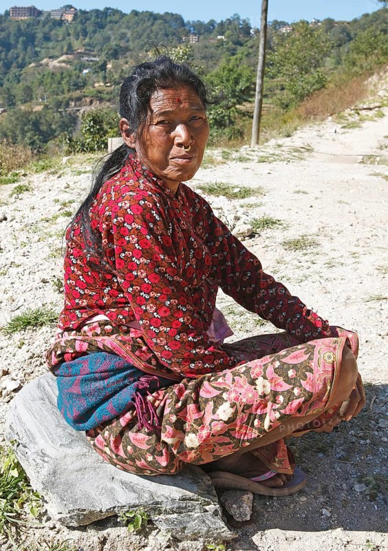 Nepalese woman with nose ring and forehead tika sitting on the ground