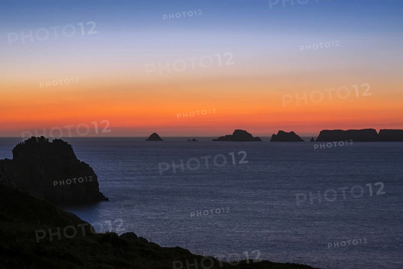 Sea cliffs at the Pointe de Pen-Hir and Les Tas de Pois sea stacks silhouetted against sunset on the Crozon Peninsula