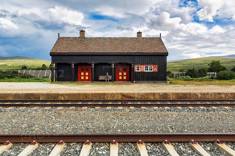 Man sitting lonely on a bench looking at the tracks